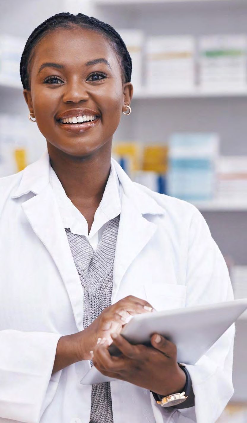 Pharmacist with a tablet in front of stocked shelves